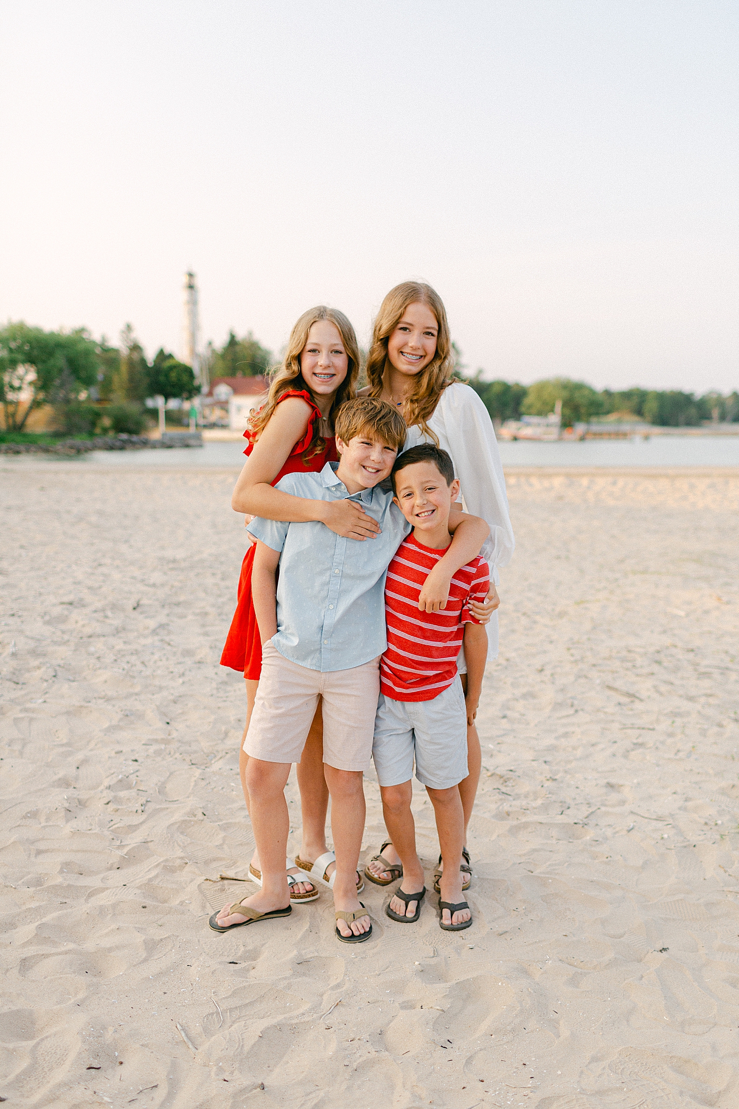 Four siblings smiling for photos on the beach at a Sturgeon Bay Canal Light Family Session