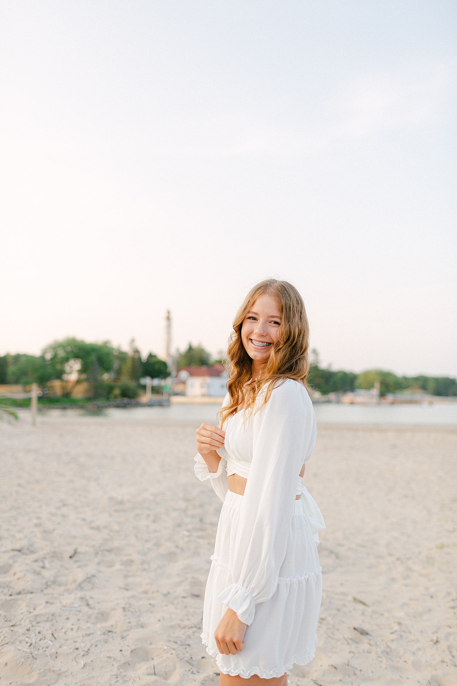 oldest sister posing in front of a lighthouse at the beach at a Sturgeon Bay Canal Light Family Session