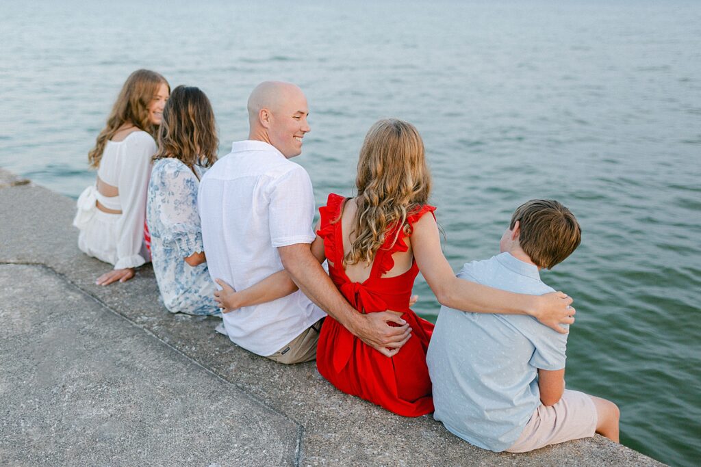 A family in coordinating 4th of July colors sitting on the pier at their Sturgeon Bay Canal Light Family Session