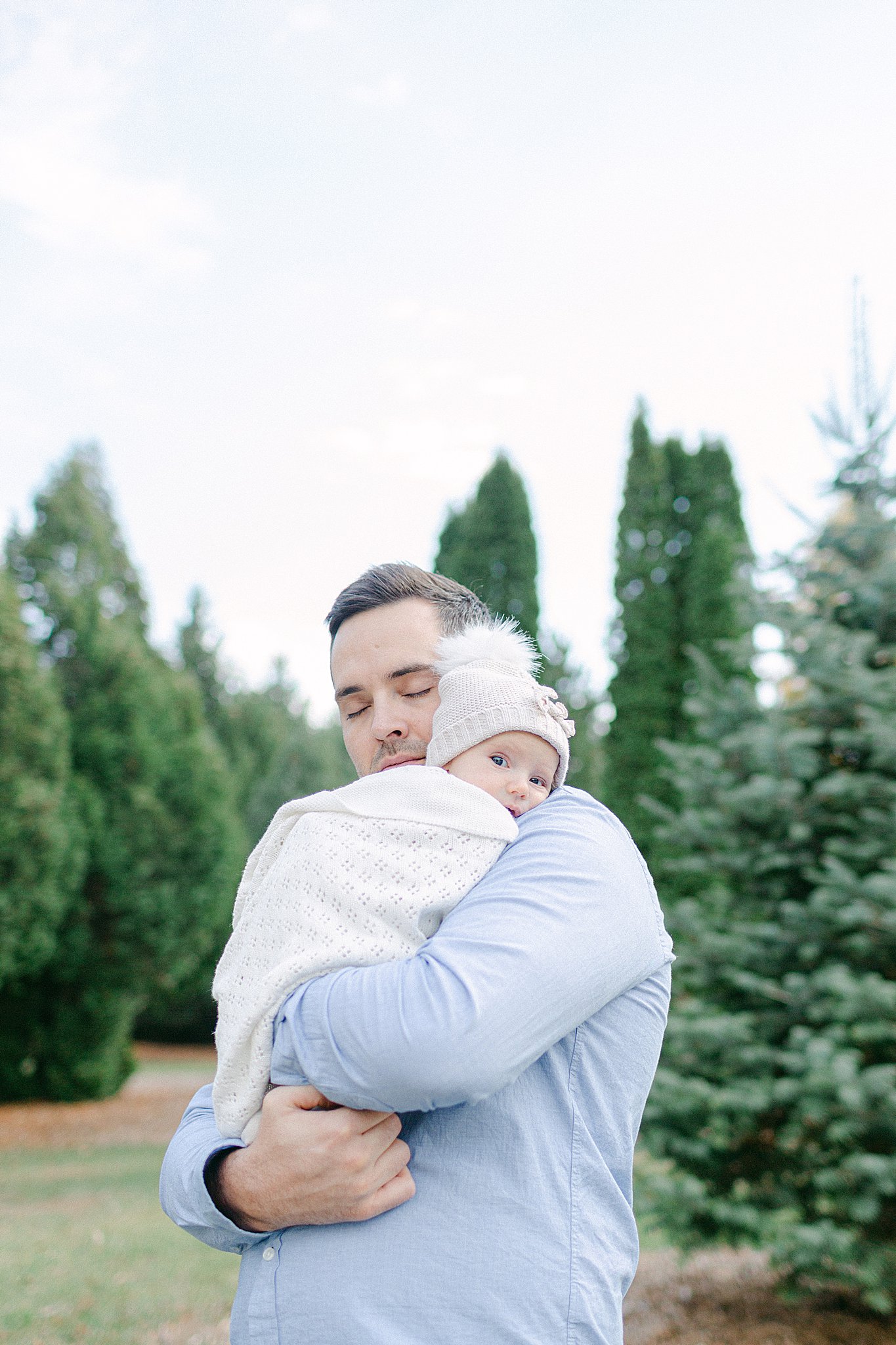 Dad cuddling baby girl all wrapped up outside at a Newborn Session in Green Bay