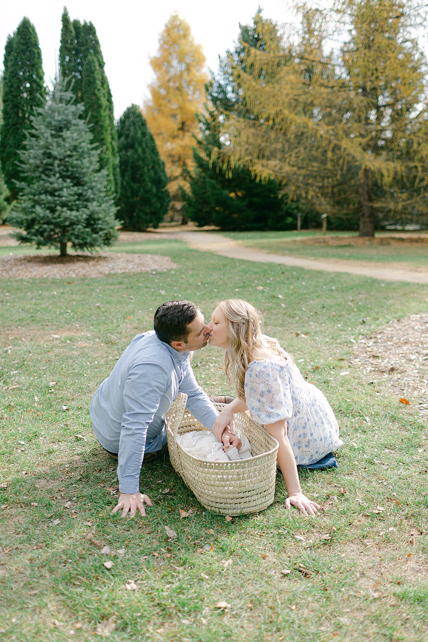 Mom & Dad kissing over baby in Moses basket at a Newborn Session in Green Bay