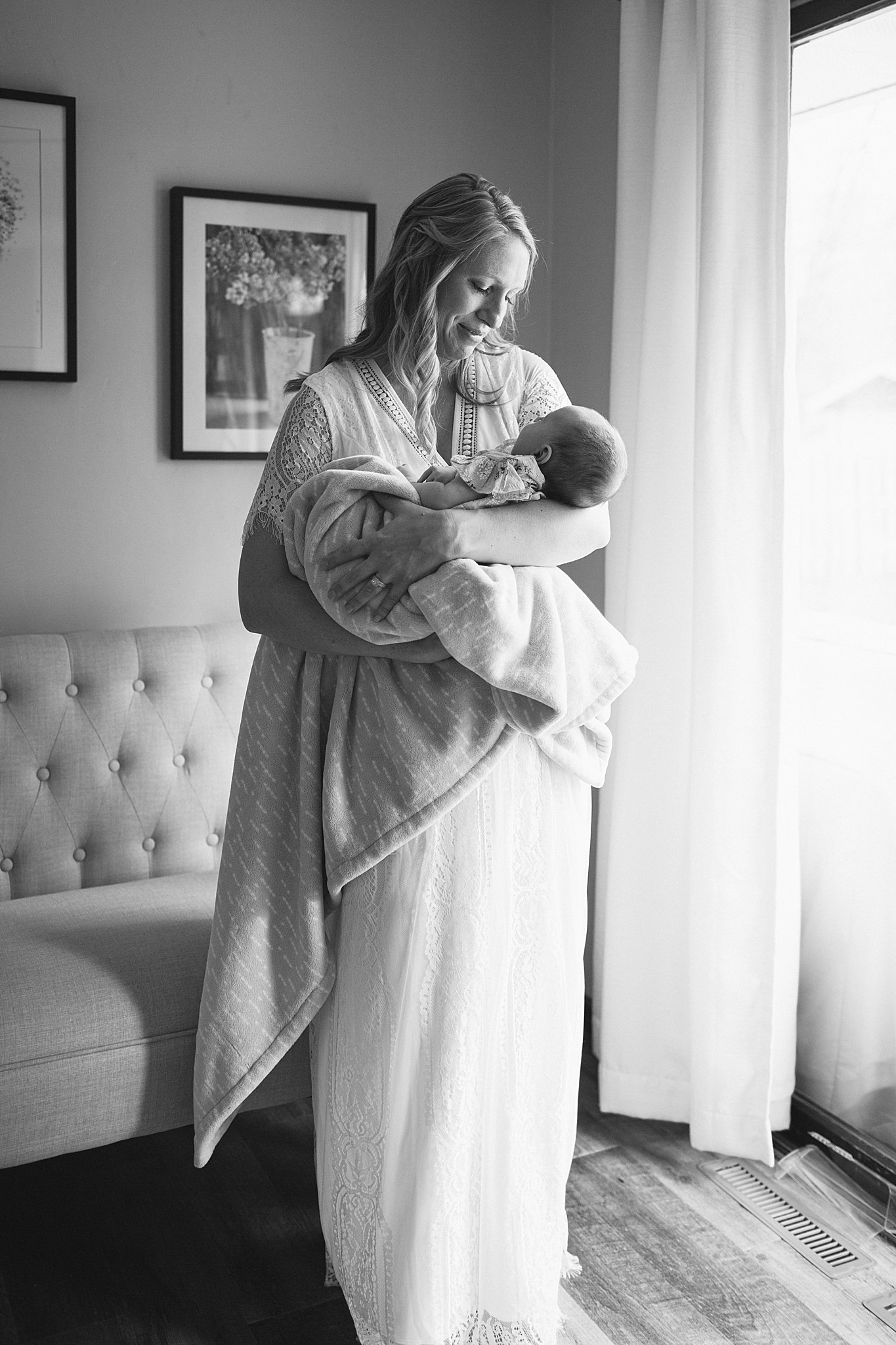 Mom holding baby while standing in front of a window at a Newborn Session in Green Bay