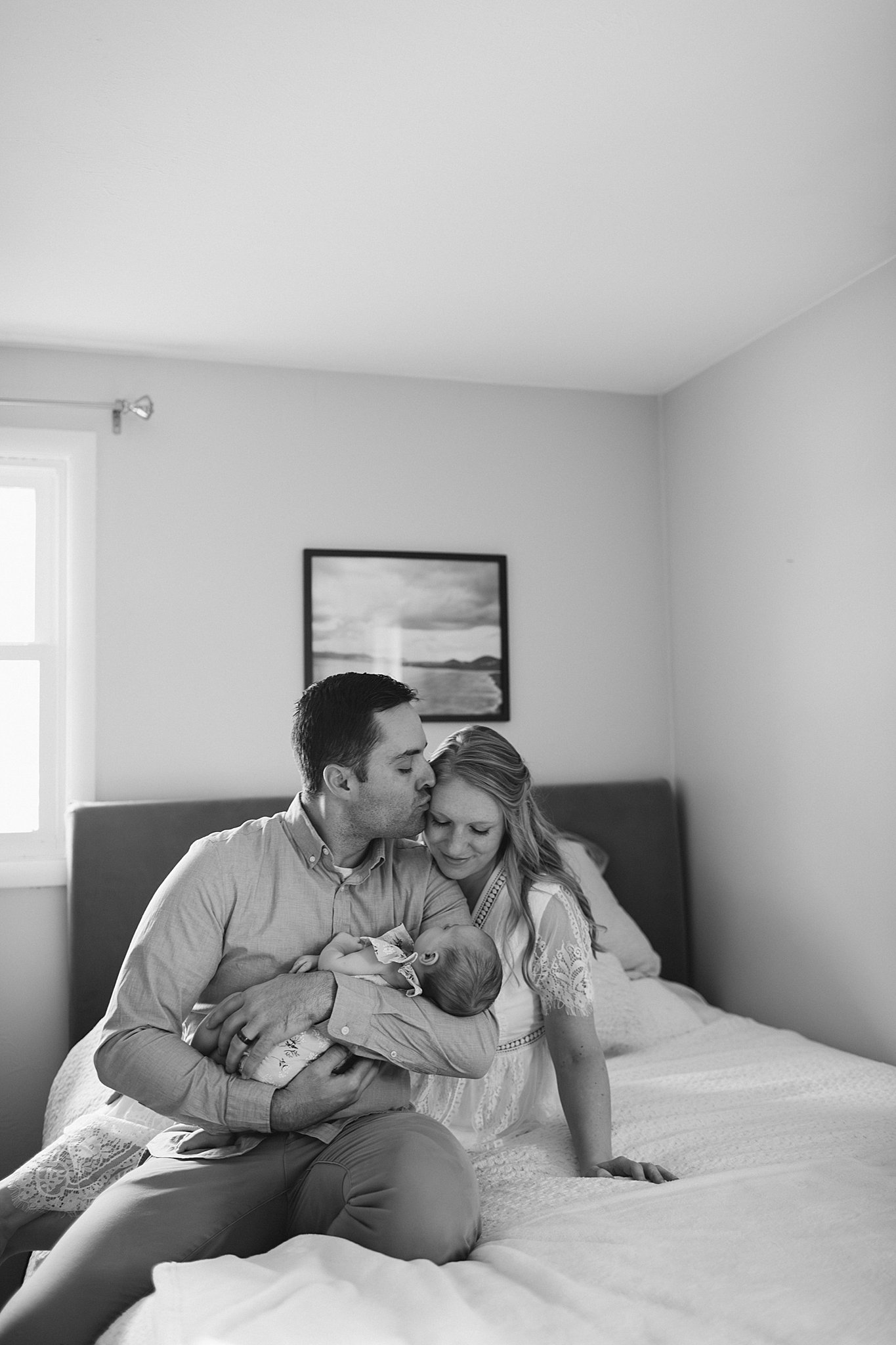 Dad kissing Mom and holding baby at a Newborn Session in Green Bay